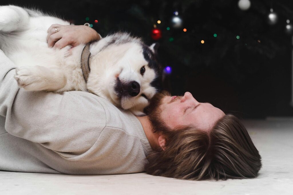 A man and his Husky dog cuddle affectionately in a cozy indoor setting.