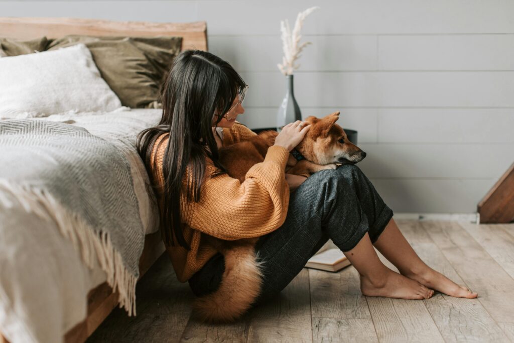 A young woman cuddles her Shiba Inu dog in a cozy indoor setting, radiating warmth and companionship.