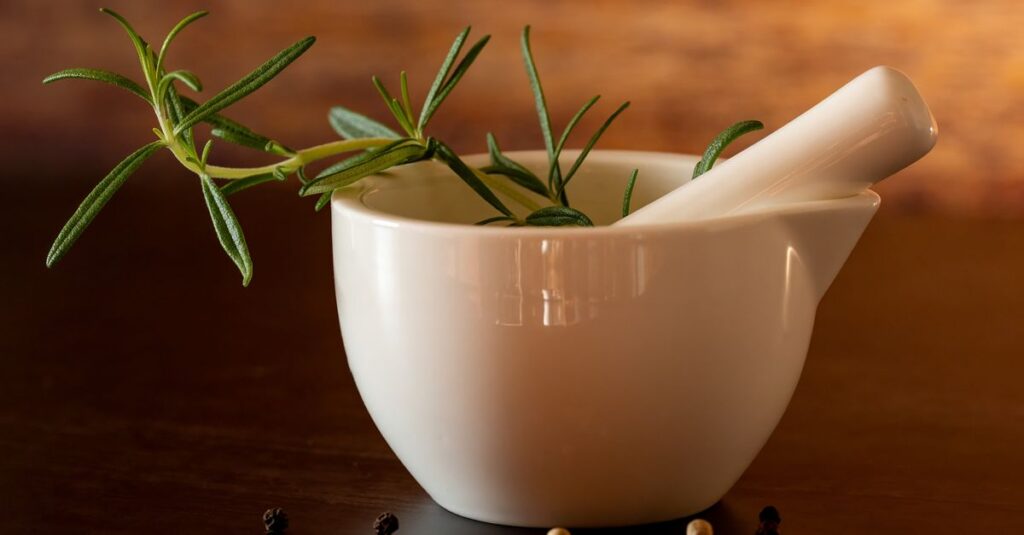 Elegant white mortar with pestle and rosemary on wooden background, perfect for culinary themes.