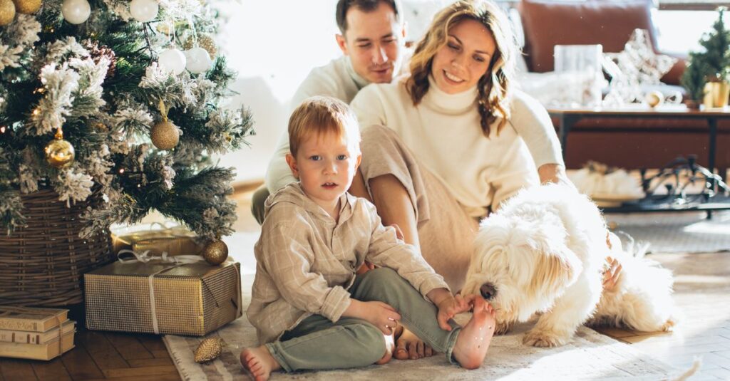 A joyful family with their pet dog celebrates Christmas morning at home by the tree.