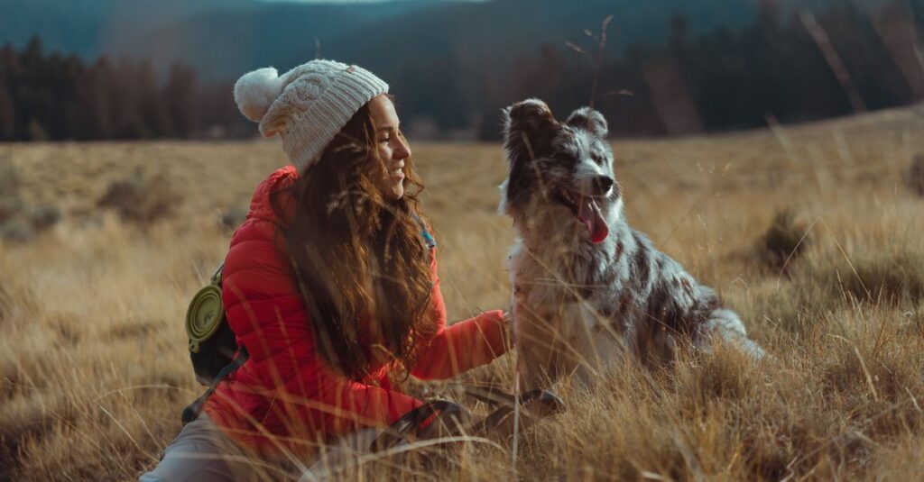 A woman and her dog enjoy a serene outdoor adventure in a grassy field.