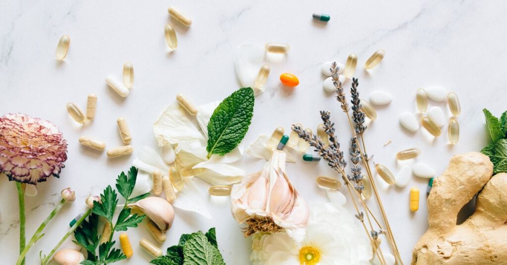 A flatlay of natural herbs, supplements, and flowers on a marble background.