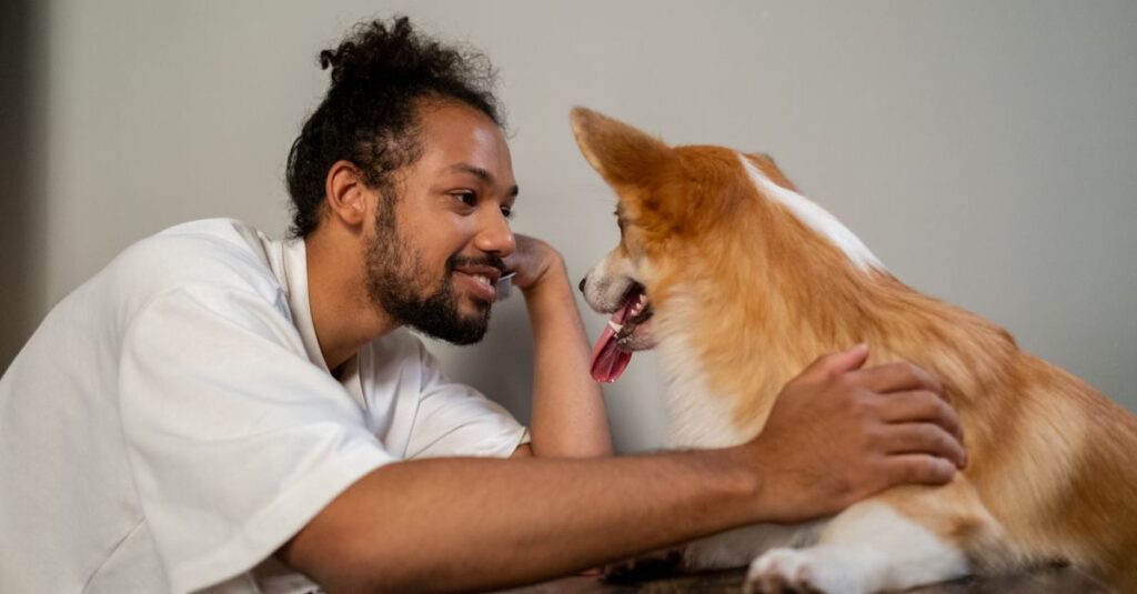 Man and corgi sharing a joyful moment indoors, showcasing self love and companionship.